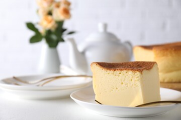 Piece of tasty Japanese Castella sponge cake and fork on white table, closeup. Space for text