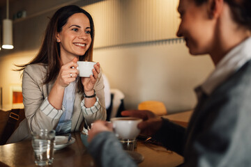 Two businesswomen drinking coffee and chatting in cafe