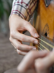 Close-up view of a musician's hands expertly positioning fingers on the strings of an acoustic...