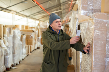 Store worker scans qr code on boxes using smartphone in warehouse