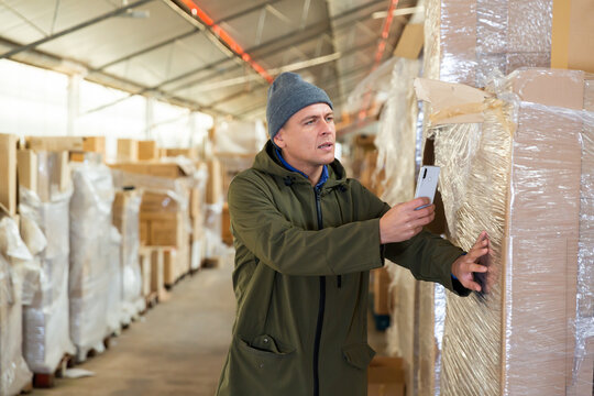 Store worker scans qr code on boxes using smartphone in warehouse