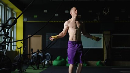 A physically fit individual engaged in performing intense rope exercises vigorously in a modern gym environment