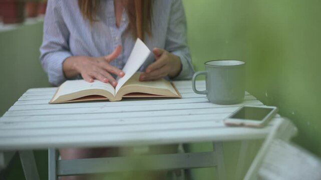 Crop woman reading book in cafe