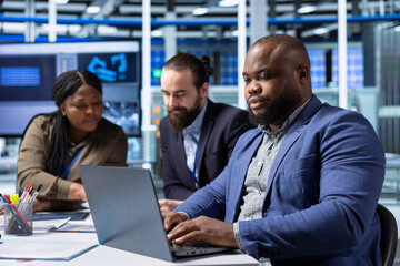 Manufacturing plant executives meeting with shareholders to review operational data on laptop. Investors look at metrics on notebook, exploring potential investment strategies for business expansion