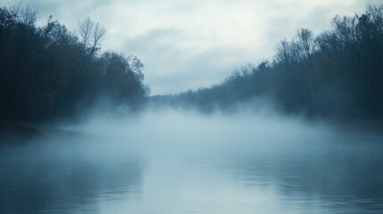 Fototapeta premium Misty river landscape at dawn, with trees silhouetted by thick fog rolling across the water
