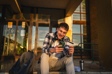 man student sit on stairs outdoor use mobile phone and credit card
