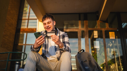 man student sit on stairs outdoor use mobile phone and credit card