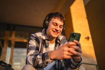 Fototapeta premium young man student sit in front university listen music and enjoy