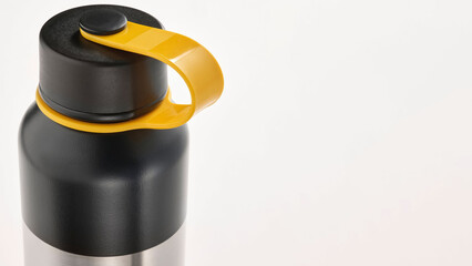Closeup of stainless black and yellow travel mugs on copy-space background.