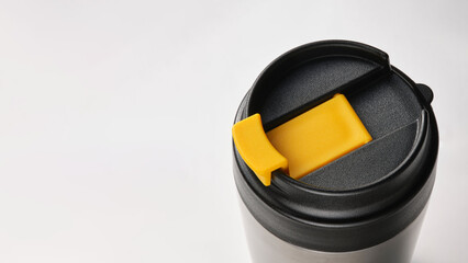 Top view closeup of stainless black and yellow travel mug on copy-space background.