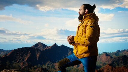 Fototapeta premium Adventure seeker in warm clothing enjoys the serenity of the wilderness, panoramic mountain top view and open sky create the perfect setting for relaxation. Cold winds uphill. Camera A.
