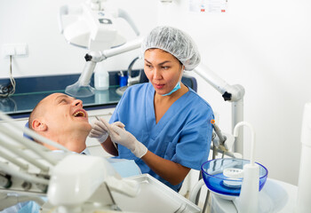 Obraz premium Positive female dentist preparing for a male oral examination