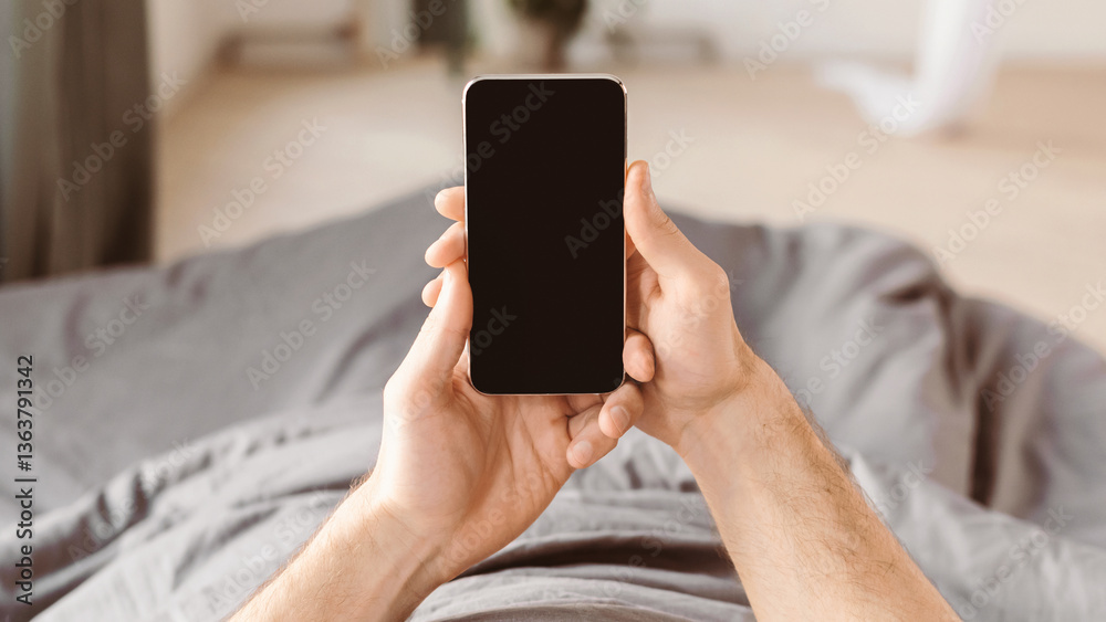 Poster unrecognizable man using smartphone with empty screen lying in bed at home. mockup, pov, panorama