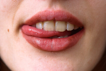 Woman biting her lip showing white teeth and pink tongue