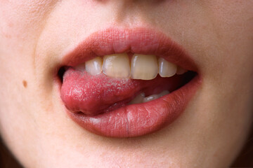 Woman licking her lips showing white teeth and pink tongue