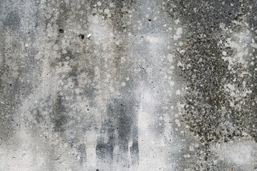 A textured concrete wall with cracks, stains, and weathered discoloration, creating an abstract and...