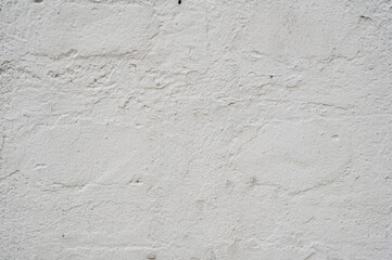 A close-up of a textured white wall with subtle imperfections and roughness. The uneven surface creates an organic, natural aesthetic, making it a versatile background or texture for design projects