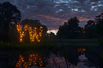 Dusk Representation of the 'YW' Chat Slang in an Illuminated Public Park Setting