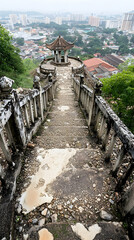Overgrown stone staircase leading to a weathered gazebo overlooking a city