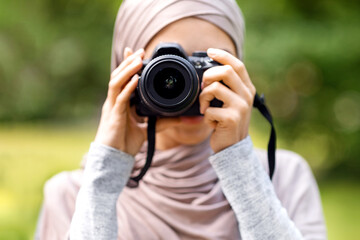 Closeup of muslim woman photographer taking photos at park, copy space