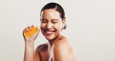 Happy woman, orange or squeeze with vitamin C for detox, skincare or nutrition on a white studio...