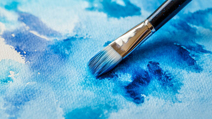 Fototapeta premium Closeup of paintbrush painting with wet watercolor paint abstract brushstrokes on textured watercolor paper many beautiful shades of blue art class creativity with copy space 