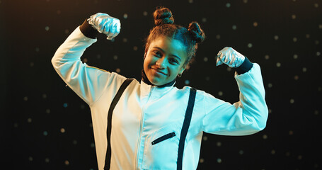 Happy girl, portrait and astronaut with flex in spacesuit at night for galaxy adventure, journey or travel. Female person, young teenager or child with arms or confidence on a dark studio background © Flashizzle/peopleimages.com