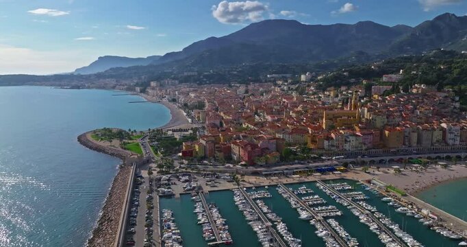 Aerial view of Menton, France. The colourful old town of Menton in summer, with historic buildings and beautiful beach at sunset. Aerial shot of historic church and colorful rooftops