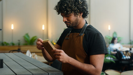 Sad man Indian Arabian guy waiter in apron cafe worker cleaner male business owner latino barista...