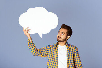 Handsome Indian man holding speech bubble with empty space for your design over lilac background