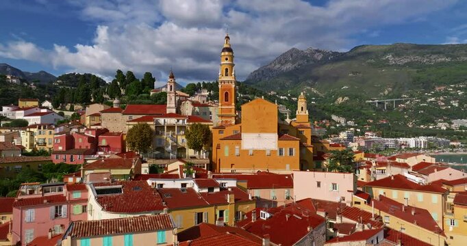 Aerial view of Menton, France. The colourful old town of Menton in summer, with historic buildings and beautiful beach at sunset. Aerial shot of historic church and colorful rooftops