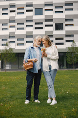 Fototapeta premium Senior couple standing on a grass in summer with straw basket and flowers
