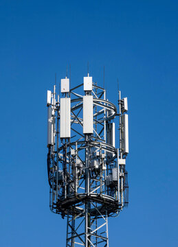 White color antenna repeater tower on blue sky close-up.