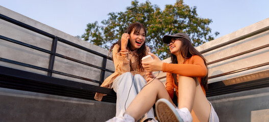 Happy Asian girl friends listening to music by cassette player, urban style mood and modern retro...