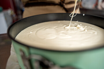 Pastry chef pouring cake batter into baking pan