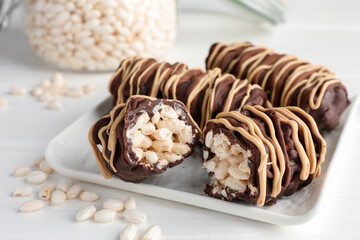 Delicious chocolate puffed rice bars on white wooden table, closeup