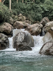Gentle River Water Flowing Over Rocks Surrounded By Lush Greenery in Leuwi Hejo