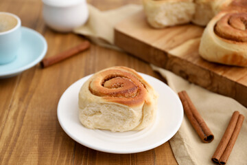 Naklejka premium Freshly baked cinnamon roll on wooden table, closeup