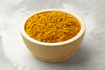 Turmeric powder in bowl on light table, closeup