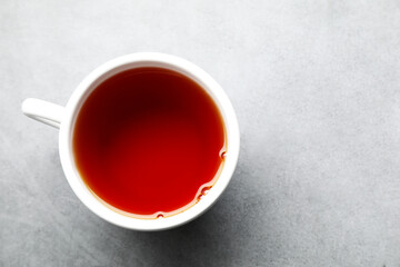 Refreshing black tea in cup on grey textured table, top view. Space for text