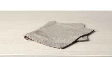 Gray napkin on light wooden table against white background