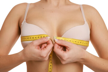 Woman in beautiful bra measuring breast circumference on white background, closeup