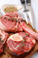Pieces of raw beef and spices on light grey table, closeup