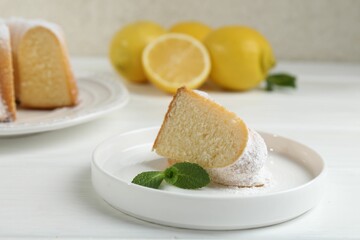 Piece of delicious lemon cake with powdered sugar and mint on white wooden table, closeup