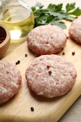 Many uncooked patties and spices on wooden table, closeup