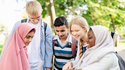 Diverse group of students study outdoors, teamwork project. Diverse students engage in learning, outdoor activity. Group of young students teamwork. Outdoor study session with diverse student group