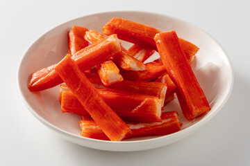 Vibrant Red Imitation Crab Sticks Served in a White Bowl on a Light Background
