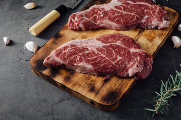 Fresh Raw Steak Cut on Wooden Board with Herbs and Garlic Ready for Cooking