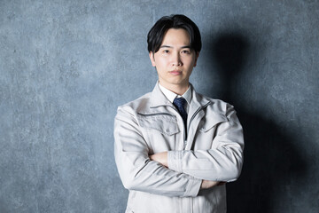 Serious and serious looking man in work clothes with folded arms Industrial image of construction management, factory, etc. There is a copy space on the left in the camera's line of sight