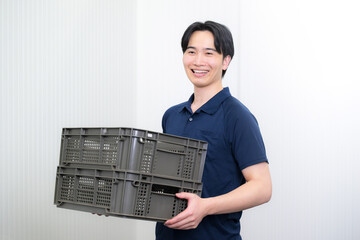 ケースやコンテナを運ぶ作業着の男性